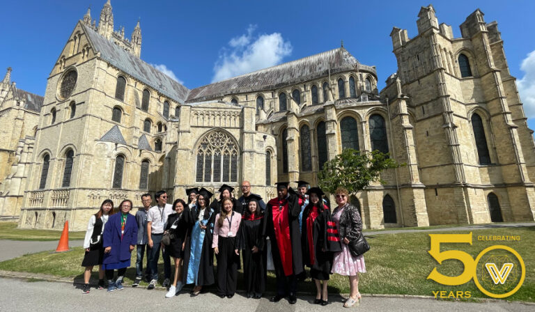 Graduands posing in front of Canterbury's namesake Cathedral