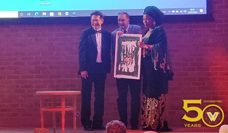 Dr Julian and Dr Brenden receiving a gift of a painting from Jamila Zanna Muhammad